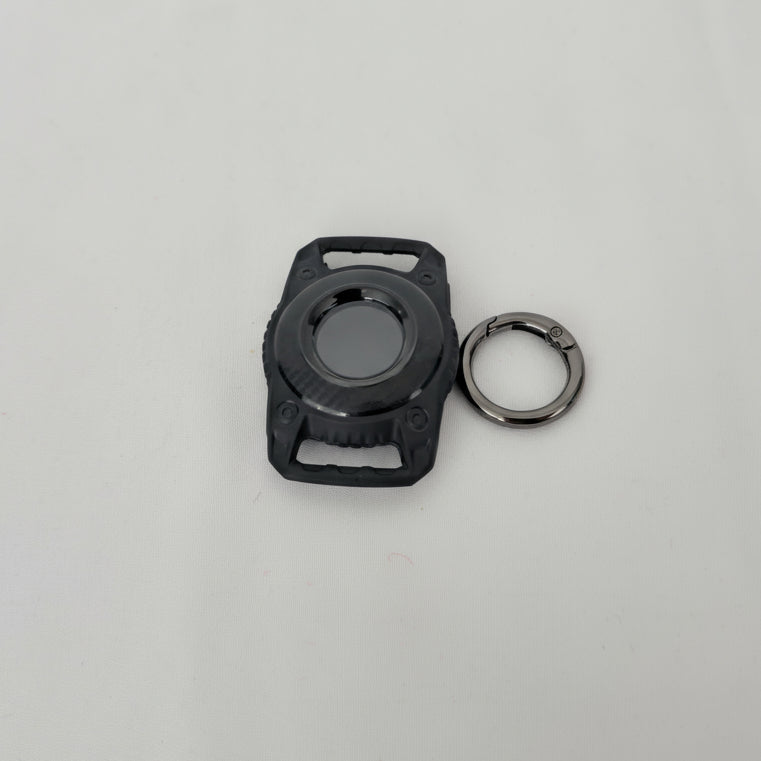 Black plastic component with a key ring on a gray background