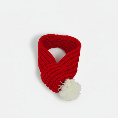 Red Christmas knitted dog scarf with soft white pom-pom, designed as a warm winter accessory for small and medium dogs.