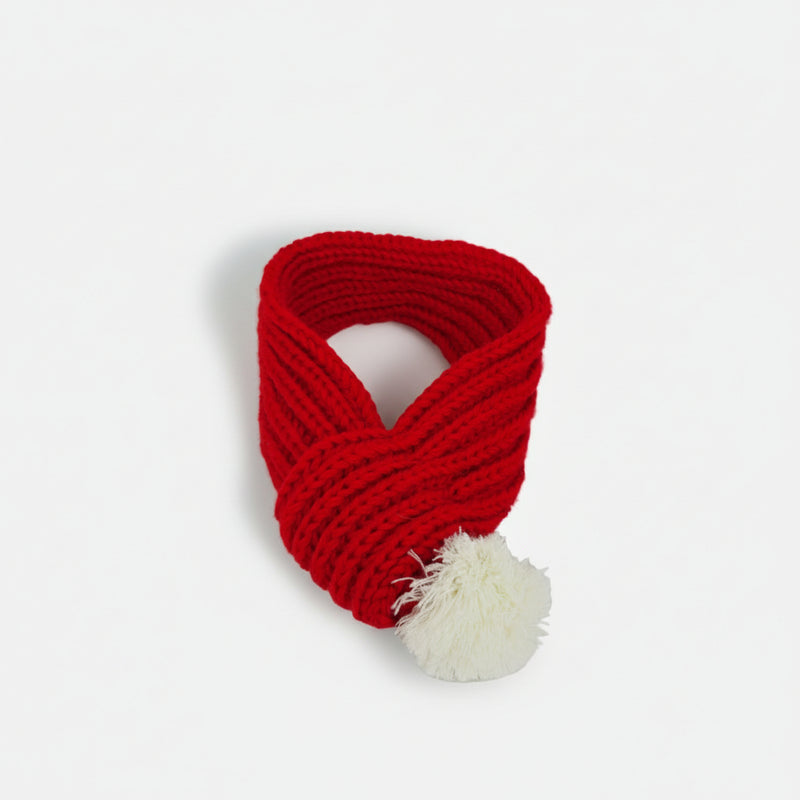 Red Christmas knitted dog scarf with soft white pom-pom, designed as a warm winter accessory for small and medium dogs.