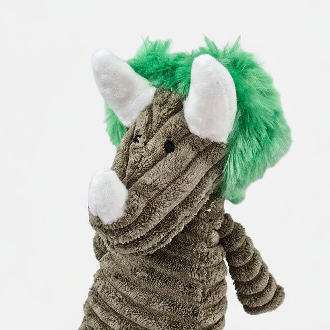 Plush dog toy resembling a dinosaur with green spikes on a white background
